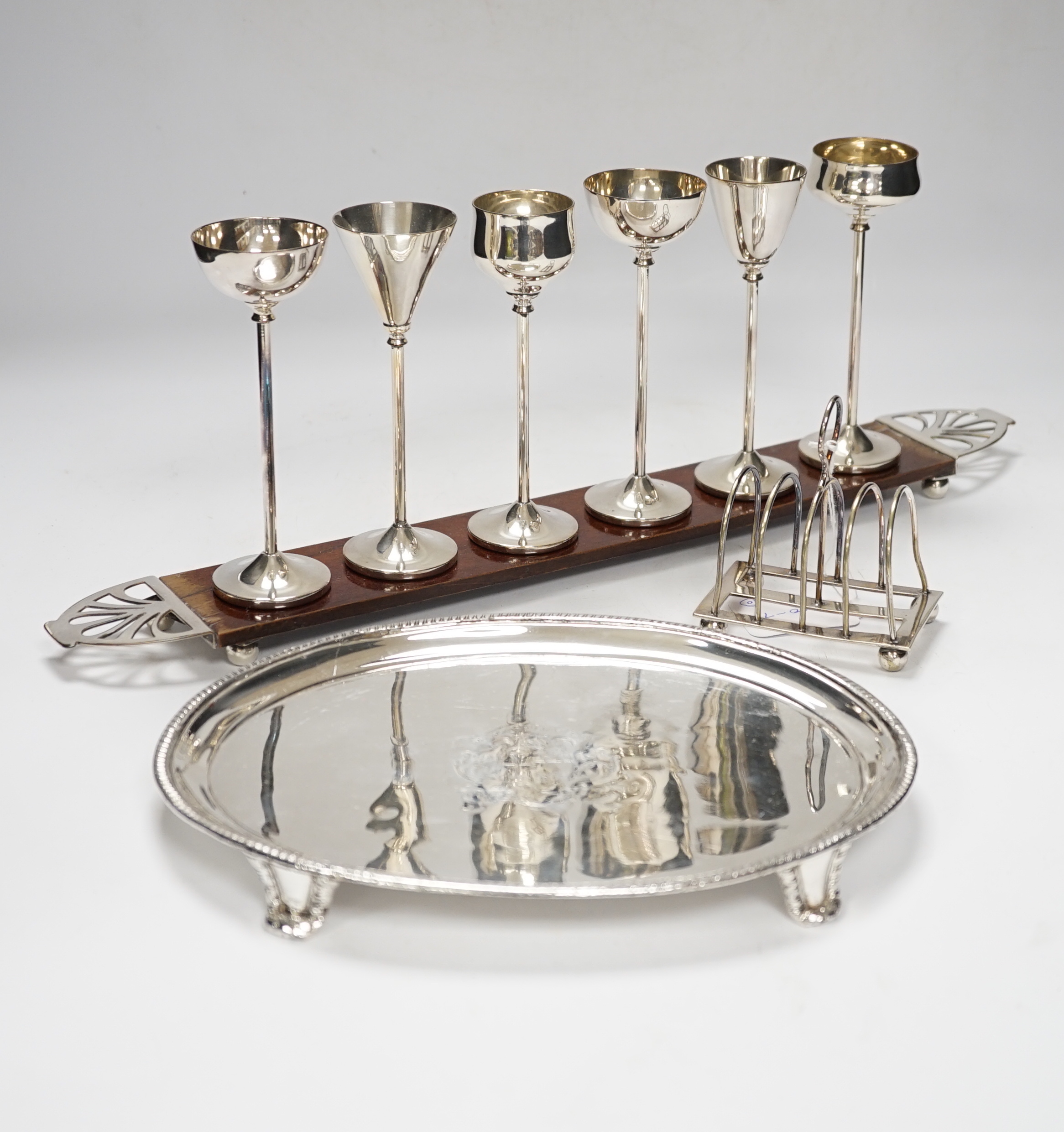 Ten silver plated items, including six good trays, a wine cooler, an Art Nouveau bowl raised on 3 feet, tray of drinking vessels, and a toast rack, largest tray 68cm